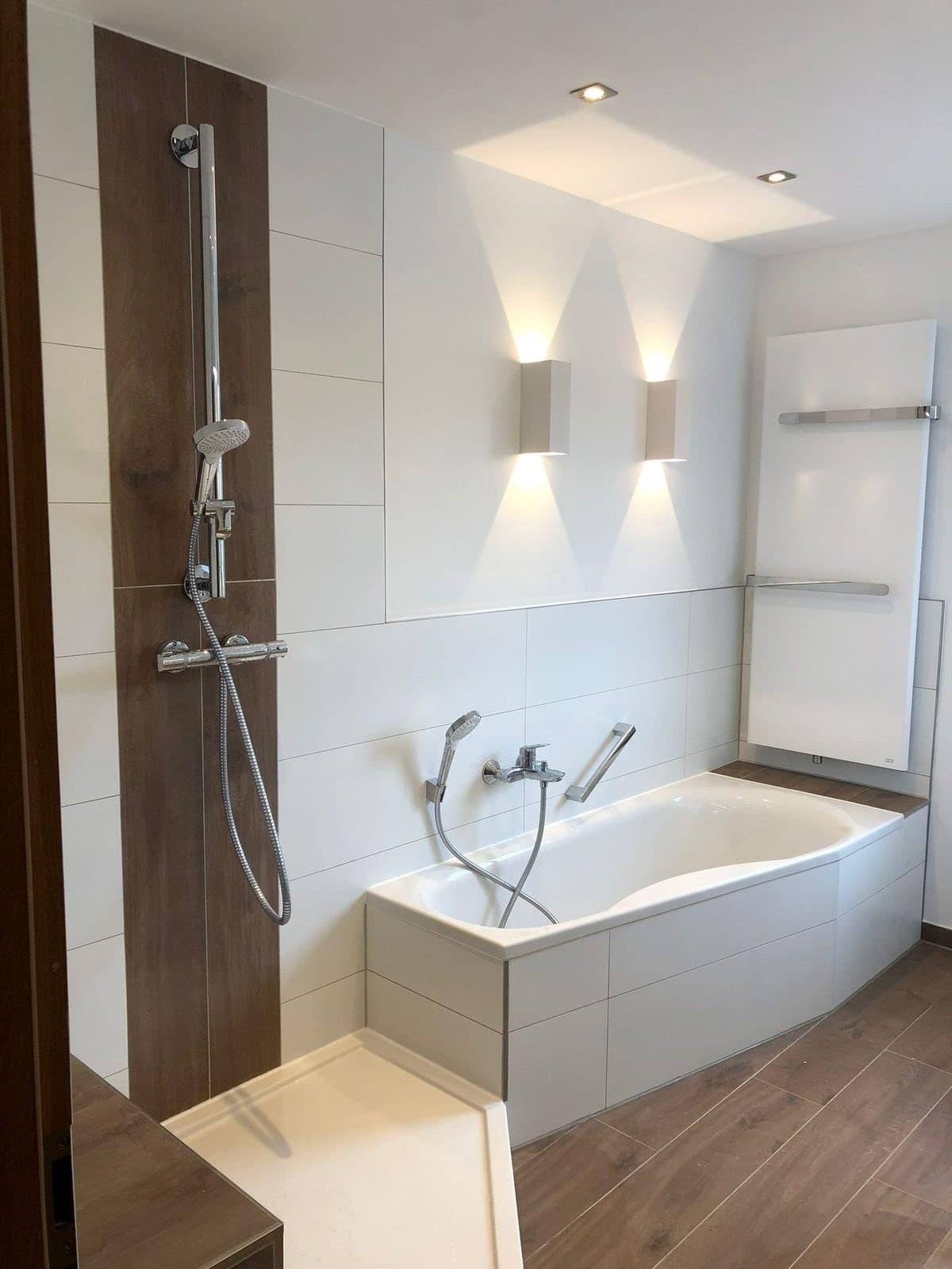 Modernes Bad mit Dusche, Badewanne und Holz-Akzentwand, Badsanierung von Kesmiris Darmstadt